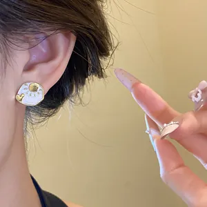 Close-up view of vintage sun and moon stud earrings with white enamel and gold details