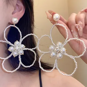 Close-up detail of oversized white pearl beaded flower pendant earrings for women