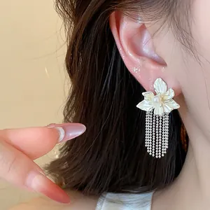 Close-up shot of elegant floral tassel pearl stud earrings with delicate hanging chains on ear