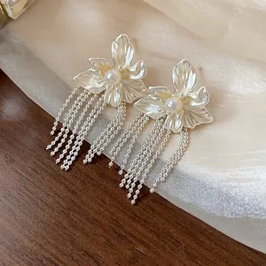 Close-up of elegant flower stud earrings with long silver tassel beads and center pearls