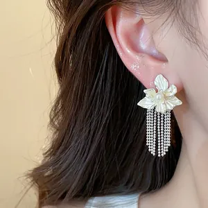 Close-up of elegant flower stud earrings with pearl and long silver tassel fringe
