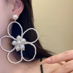 Close-up detail of large French vintage pearl beaded flower dangle earrings on ear