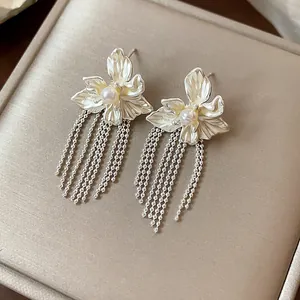 Detailed close-up of elegant silver flower earrings with pearl accents and long beaded tassels