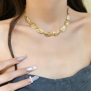Vista detallada de un collar metálico dorado con diseño arrugado elíptico en modelo