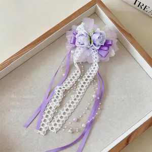 Exquisite Nahaufnahme einer lila Spitzenblumen-Haarspange mit Perlen und langen Seidenbändern