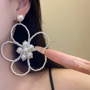 Detailed view of French retro pearl beaded flower openwork pendant earring on model's ear