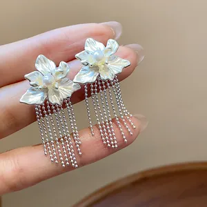 Detailed view of silver flower earrings with pearl centers and bead-chain tassels