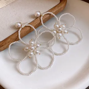 Detailed view of French vintage hollow flower earrings handcrafted with white pearl beads.