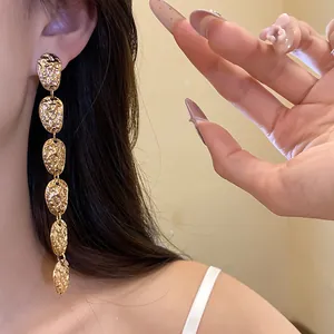 Vista detallada de elegantes pendientes largos de oro con diseño ovalado plisado