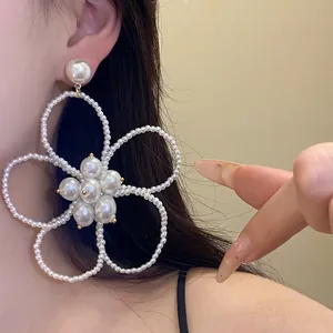 Close-up detail of large French vintage pearl beaded flower dangle earrings on ear