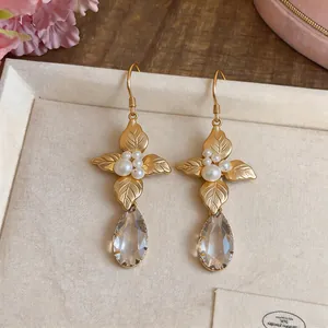 Detailed close-up of French vintage gold leaf earrings with white pearls and teardrop crystals