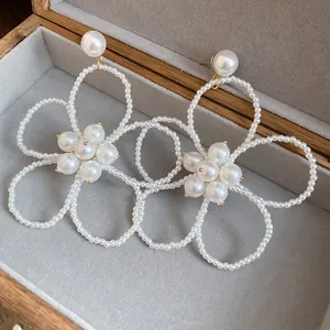 Detailed macro view of elegant oversized pearl beaded flower drop earrings in a box