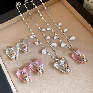 Detailed view of flocked bear pendants with heart-shaped resin and pearls on silver chains.