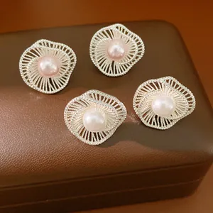 Dettaglio di orecchini a perno con fiori intrecciati e perle in argento e rosa