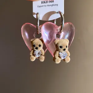 Close-up of pink heart earrings with cute flocked teddy bear and heart crystal
