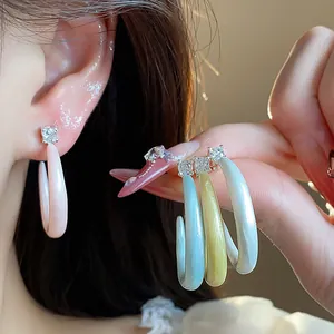 Detalle de cerca de elegantes pendientes en forma de C esmaltados con detalles de circonita