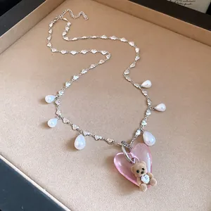 Close-up of a vintage pink heart necklace featuring a cute flocked teddy bear pendant