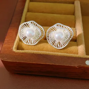 Primo piano di eleganti orecchini a lobo a fiore argento con una perla bianca centrale