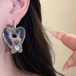 Detailed view of a retro style earring featuring a clear heart and brown flocked bear.