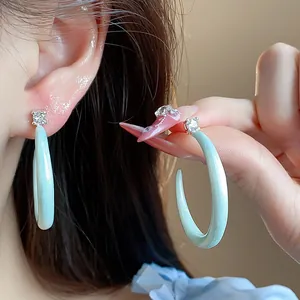 Detalle de pendientes en forma de C de esmalte verde menta con un brillante circón.
