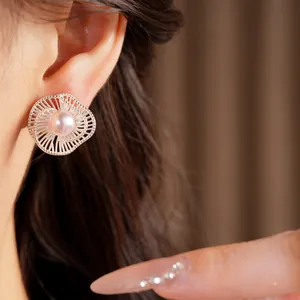 Dettaglio dell'elegante orecchino a fiore d'argento con perla rosa sull'orecchio del modello