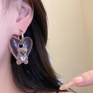 Detailed close-up of a cute flocked teddy bear earring with a pink translucent heart pendant