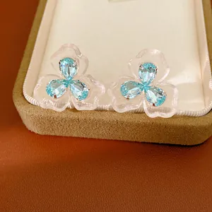Detailed macro shot of elegant blue zircon flower earrings with transparent resin petals