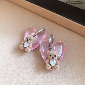 Detailed close-up of pink heart earrings with cute brown flocked teddy bear and crystal