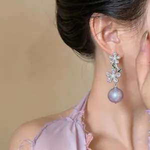 Close-up detail of elegant French zircon flower earrings with a purple pearl.