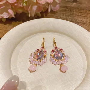 Élégantes boucles d'oreilles ethniques dorées avec cristaux roses et fleurs