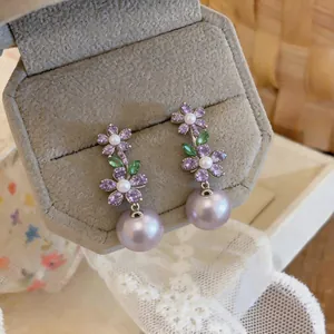 Close-up of French luxury flower drop earrings with purple zircon and lavender pearls.