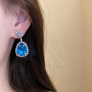 Close-up of elegant pear-shaped blue crystal drop earrings worn on a model