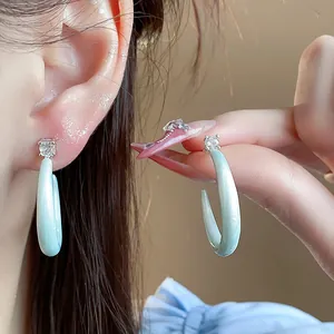 Detalle de pendientes en C de plata con esmalte verde menta e incrustación de circón.