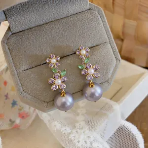 Close-up of elegant purple zircon flower earrings with large grey pearl drops
