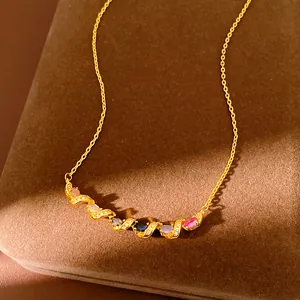 Detail view of a gold-plated necklace featuring a twisted pendant with colorful zircons.