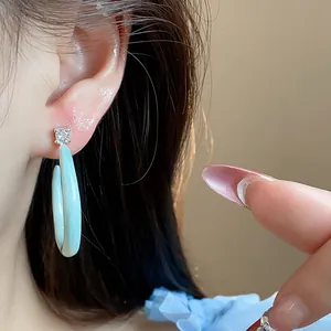 Detalle de pendientes en forma de C de esmalte azul claro con brillante de circón.