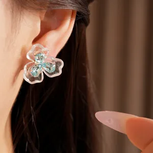 Elegant close-up view of blue resin flower stud earring with zircon on model's ear