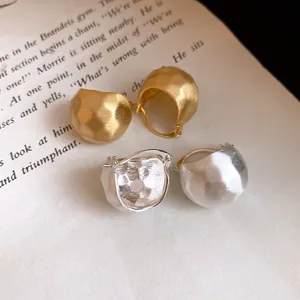 Detailed view of brushed semi-circular gold and silver hoop earrings on vintage book