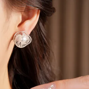 Primo piano di eleganti orecchini a fiore intrecciato in argento con perla sull'orecchio