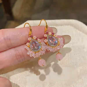 Gros plan de boucles d'oreilles à pompons en zircon rose avec pierres en goutte d'eau