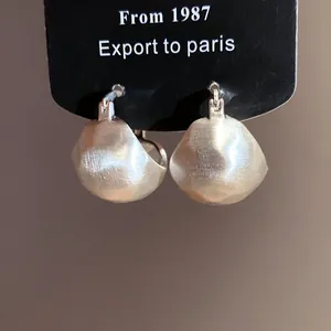 Close-up detail of vintage brushed silver semi-circular earrings on a display card