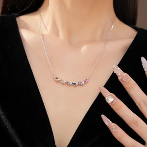 Detailed view of a silver twisted necklace with colorful zircons on a model's neck.