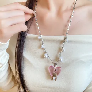 Close-up of retro pearl necklace with pink heart and flocked bear pendant