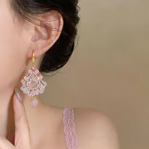 Gros plan détaillé d'élégantes boucles d'oreilles à pampilles en zircon rose et motif floral