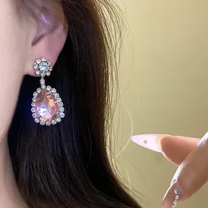 Close-up of elegant pink waterdrop pendant earring with shimmering crystal accents