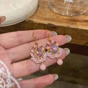 Vue détaillée de boucles d'oreilles ethniques en or avec pierres roses et fleurs
