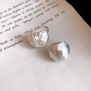 Detailed close-up of brushed silver semi-circular earrings resting on a vintage book page