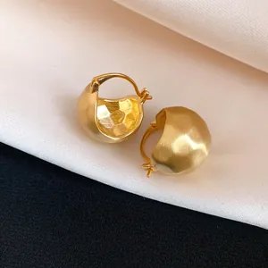 Macro detail of vintage golden brushed semi-circle hoop earrings with elegant matte finish