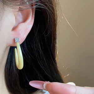 Detalle de primer plano de un pendiente de aro en C en esmalte amarillo pálido con circón