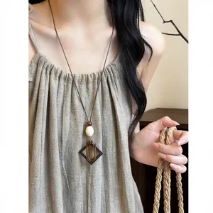 Detail of long leather cord necklace with vintage ethnic resin and acrylic pendant.